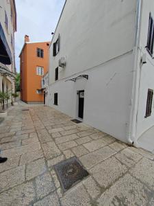 Une allée avec un bâtiment blanc et une porte dans l'établissement Tequila Apartments, à Zadar