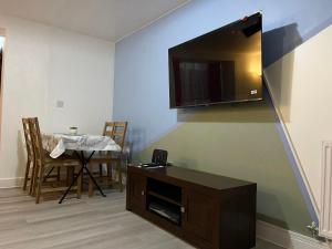 ein Wohnzimmer mit einem Tisch und einem TV an der Wand in der Unterkunft Crescent Apartment - Two bedroom in Goodmayes