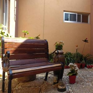 a wooden bench sitting in front of a building with potted plants at Lake road Apartment in Lusaka