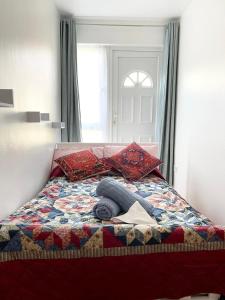 ein Bett mit einer Decke und Kissen darauf in der Unterkunft Crescent Apartment - Two bedroom in Goodmayes
