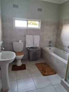 a bathroom with a toilet and a tub and a sink at Lake road Apartment in Lusaka