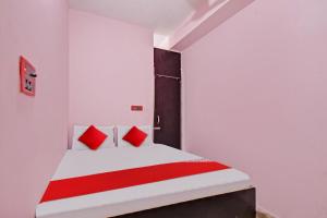 een slaapkamer met een wit bed met rode kussens bij Flagship Red Rose Hotel & Banquet in Dhanbad