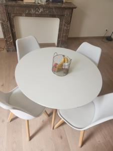 una mesa blanca con 2 sillas y una cesta de fruta en Chambre disponible en Bruselas