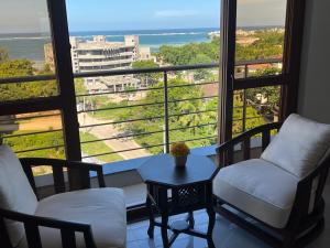 um quarto com duas cadeiras e uma mesa e uma grande janela em Penthouse Living em Mombasa