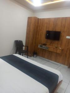 1 dormitorio con 1 cama y TV en la pared en hotel gateway inn en Ahmedabad