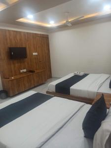 1 dormitorio con 2 camas y TV de pantalla plana en hotel gateway inn en Ahmedabad