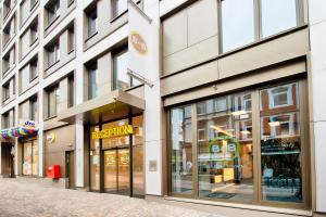 uma loja na frente de um edifício com janelas de vidro em B&B Hotel Aachen-City em Aachen