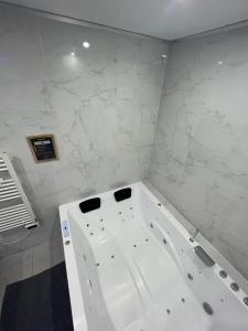 a white bath tub in a bathroom with marble walls at Room & Jacuzzi - Stade de France in Saint-Denis