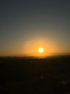 einen Sonnenuntergang über einem Feld mit der Sonne am Himmel in der Unterkunft WARZAZAT Hostel in Ouarzazate