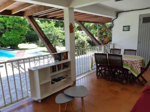 a screened in porch with chairs and a table and a table at Bas de villa, hauteurs du Robert in Le Robert