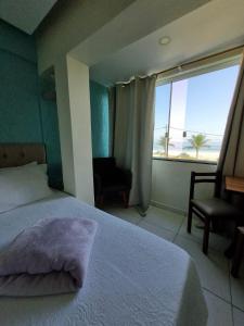 a bedroom with a bed and a window with a view of the beach at Hotel Aconchego Da Vila in Saquarema