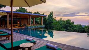 a pool at a resort with tables and an umbrella at Sanglung Villas & Suites in Kubutambahan
