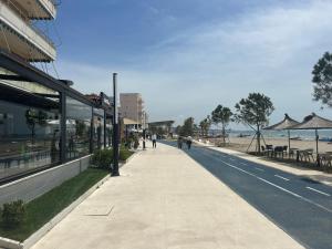 a sidewalk next to a beach with people walking on it at Vacation house villa roni in Durrës