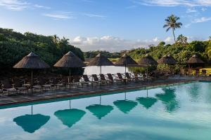 uma piscina de resort com cadeiras e guarda-sóis em San Lameer Villa 14110 - 5 Bedroom Luxury - 10 pax - San Lameer Rental Agency em Southbroom