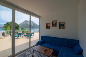 a living room with a blue couch and a balcony at Adrasan Hotel in Kumluca