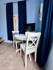 エルミオニにあるBlue Loft by Gcollectiongrの青いカーテン付きの客室で、白いテーブルと椅子が備わります。