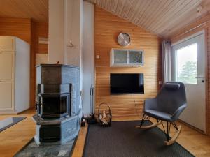 a living room with a fireplace and a chair at Kuukkeli Apartments Suite in Saariselka