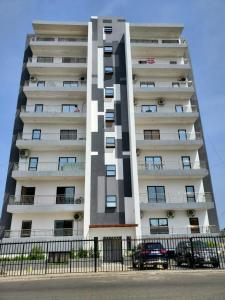 a tall white apartment building with cars parked in front of it at Star tower in Accra