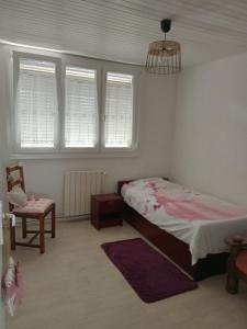 Un dormitorio con una cama y una silla y ventanas. en Bienvenue, en Marly