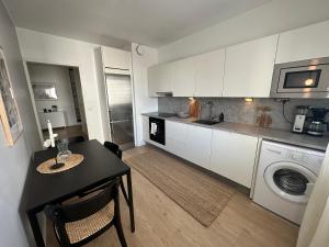 a kitchen with white cabinets and a table and a sink at Arctic City Apartment in Rovaniemi