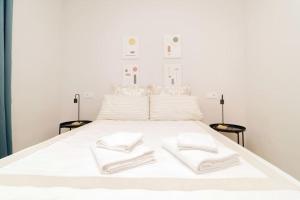 Una cama blanca con dos toallas blancas. en Encanto Celestial en Santa Úrsula en Madrid