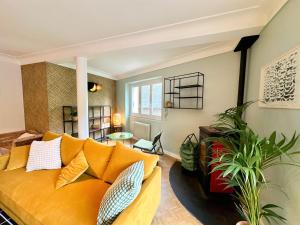 sala de estar con sofá amarillo y planta en Bel appartement 100 m2 / Parking / Paisible, en Rodez