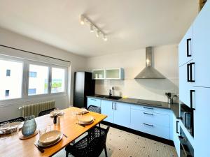 cocina con mesa de madera y cocina con armarios azules en Bel appartement 100 m2 / Parking / Paisible, en Rodez