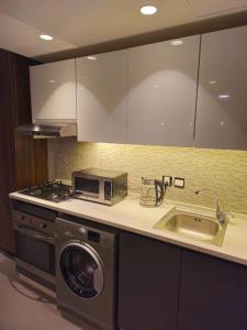 a kitchen with a washing machine and a sink at Luxury Apartments - Damac Tower Amman in Amman