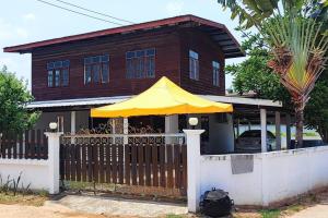 uma casa com um guarda-chuva amarelo em frente a uma cerca em บ้านพักในสวนK&N1 