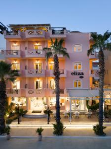 a hotel with palm trees in front of it at Eliza Hotel by Panel Hospitality - Formerly Evdion Hotel in Nei Poroi