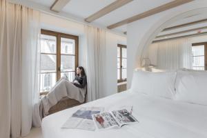 a woman sitting in a chair in a room with two beds at Hôtel de La Cigogne in Saint-Ursanne +18 photos