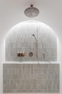 y baño con ducha y azulejos grises. en Hôtel de La Cigogne en Saint-Ursanne