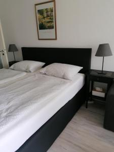 シュタインフーデにあるFerienwohnung Resit 3のベッドルーム(白いベッド、黒いヘッドボード付)