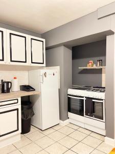 uma cozinha com armários brancos e um frigorífico branco em Shepherds House - 3 Bedroom em Goodmayes
