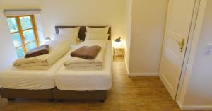 una camera da letto con un letto con lenzuola e cuscini bianchi di Lieblingsplatz a Grömitz