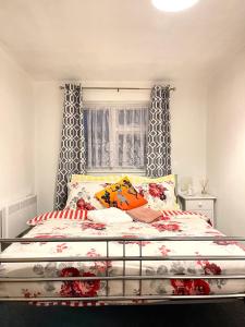 Shepherds House - 3 Bedroom في Goodmayes: غرفة نوم بسرير كبير مع شراشف حمراء وبيضاء