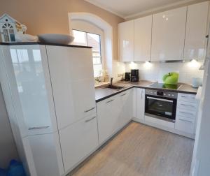 een witte keuken met witte kasten en een houten vloer bij Teichhaus - 6033 in Grömitz