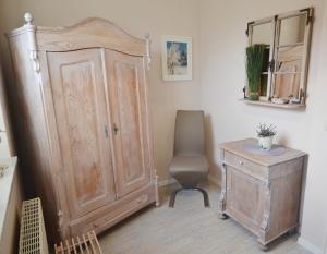 een kamer met een grote houten kast en een stoel bij Teichhaus - 6033 in Grömitz