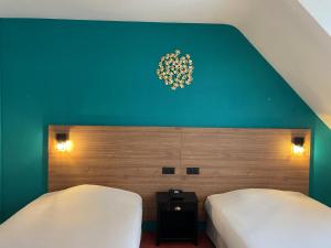 1 dormitorio con 2 camas y pared verde en Hotel Le Progres, en Angers