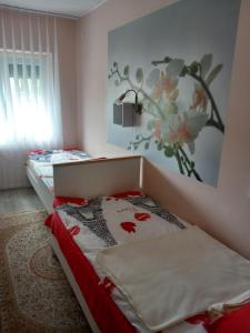 sypialnia z łóżkiem z obrazem kwiatowym na ścianie w obiekcie Ria Vendégház w Mezőkövesd