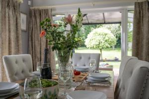 a dining room table with a vase of flowers on it at Oak Lodge in Burley