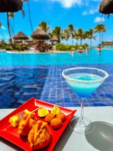 a red plate of food and a drink next to a pool at Enotel Porto de Galinhas All Inclusive in Porto De Galinhas