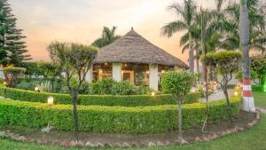 a resort building with a thatched roof at Corbett Fun Resort in Rāmnagar