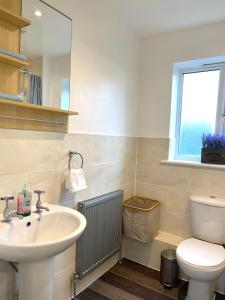 a bathroom with a sink and a toilet and a window at Forsyth Court Apartment - Two bedroom in Dagenham