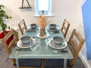 a green table with plates and bowls on it at The Grand Forsyth Apartment - Two bedroom in Dagenham +3 photos
