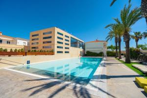 a swimming pool in front of a building with palm trees at Kampaoh Kikopark Playa in Oliva