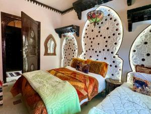 sypialnia z 2 łóżkami i ścianą w stylu marokańskim w obiekcie Riad Mogador w mieście Meknès