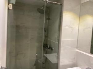 a shower with a glass door in a bathroom at Splendid Apartments - Embassy Gardens in Accra