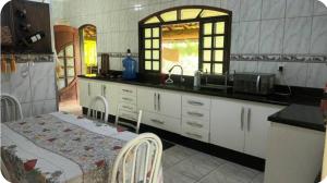 eine Küche mit einem Waschbecken und einem Tisch darin in der Unterkunft Chácara Tavares em São Roque in Taxaquara
