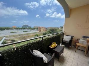 einen Balkon mit Stühlen, Tischen und Aussicht in der Unterkunft Appartamento vista mare in Albenga